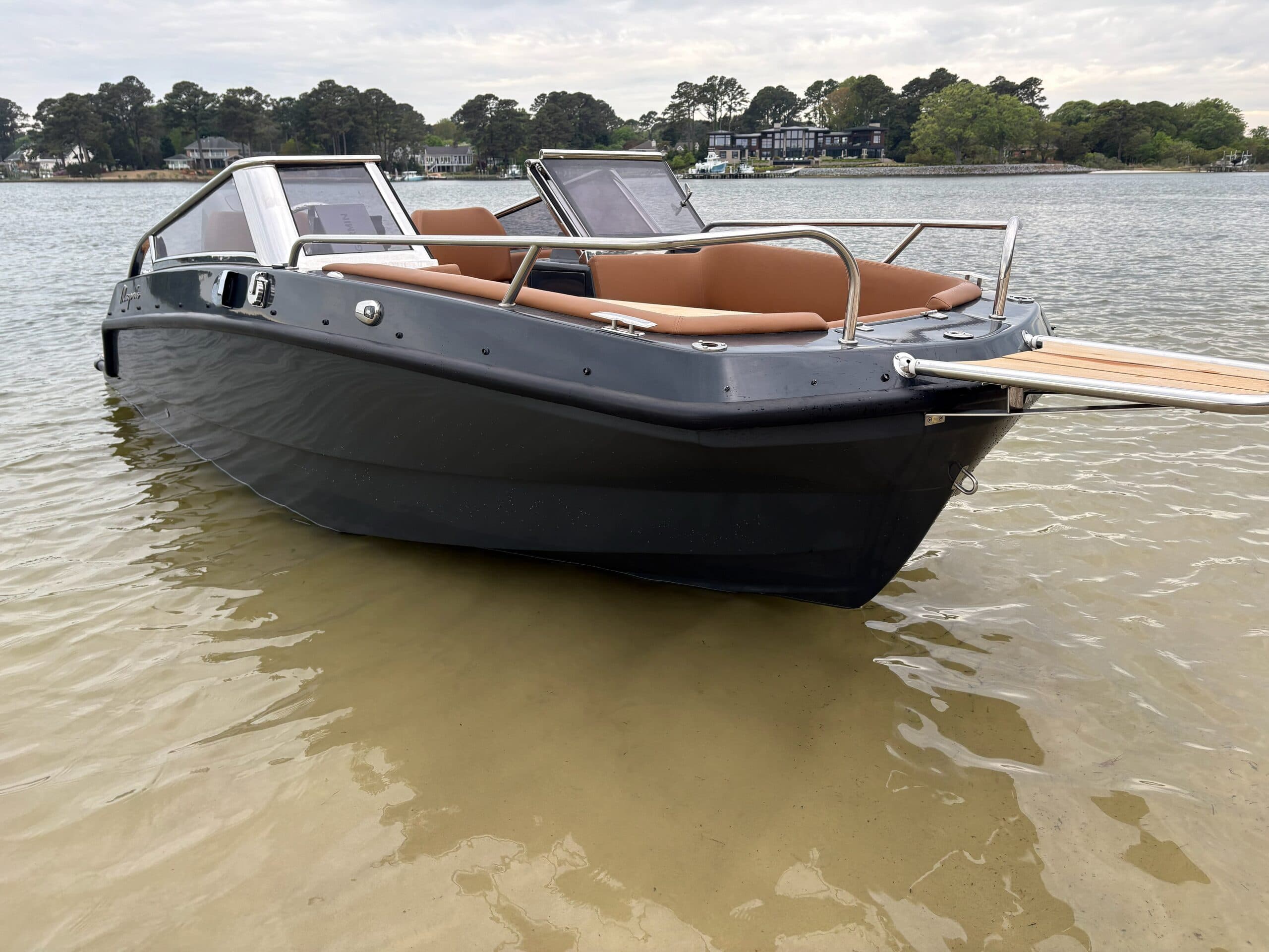 bow and side of the magonis boat charcoal hull with brown interior beached in low tide trees in background